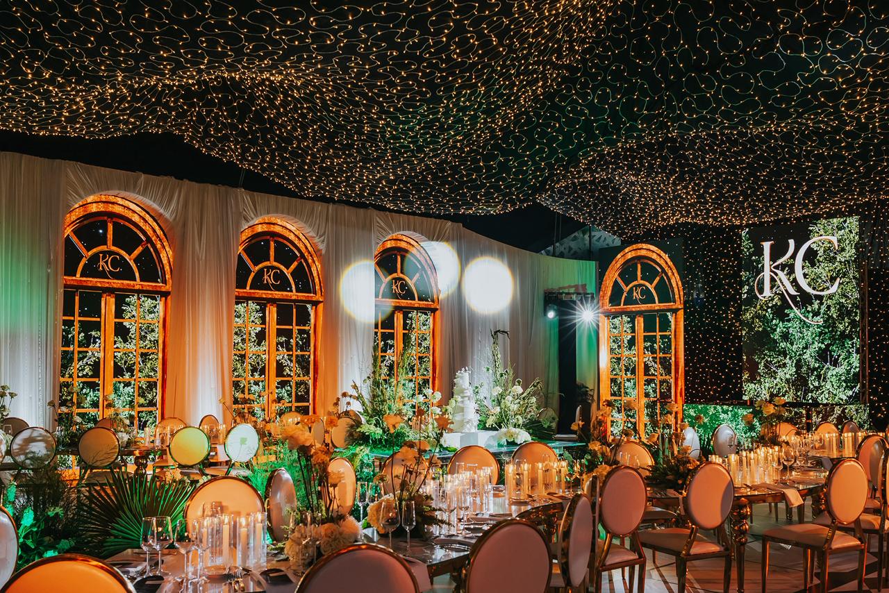 Recepción de boda con velas, cristalería y ventanales iluminados