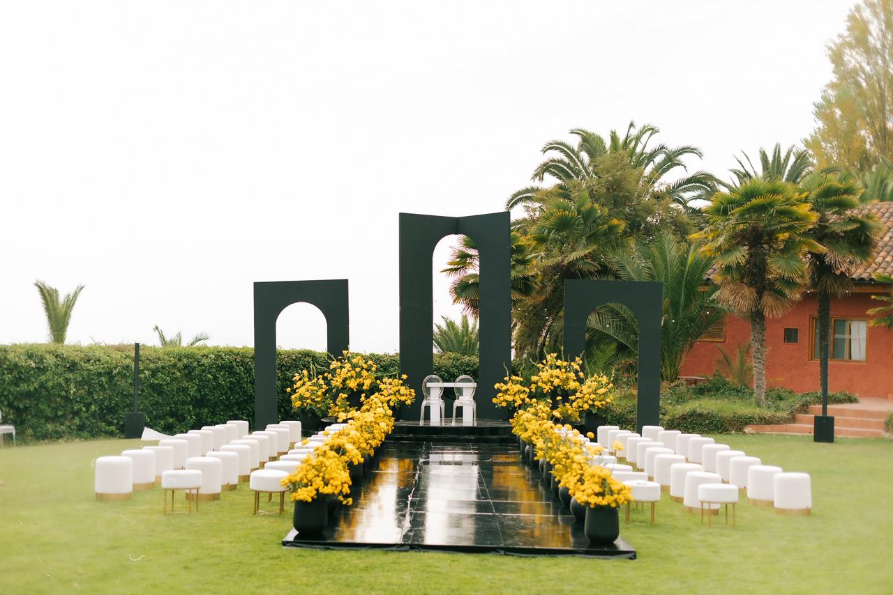 Ceremonia al aire libre con arcos negros y flores amarillas