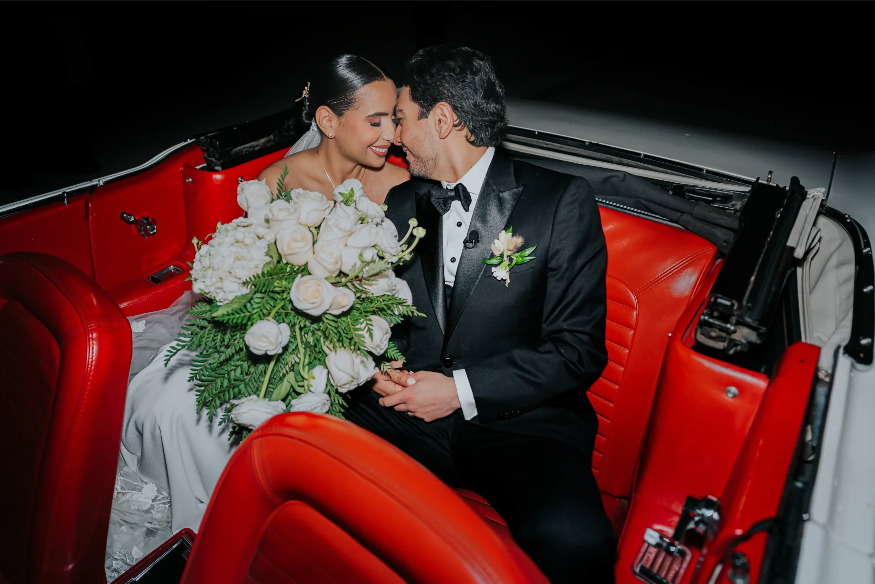 Boda Exequiel y Mireya, novios en un auto clásico descapotable de tapizado rojo con ramo de rosas blancas