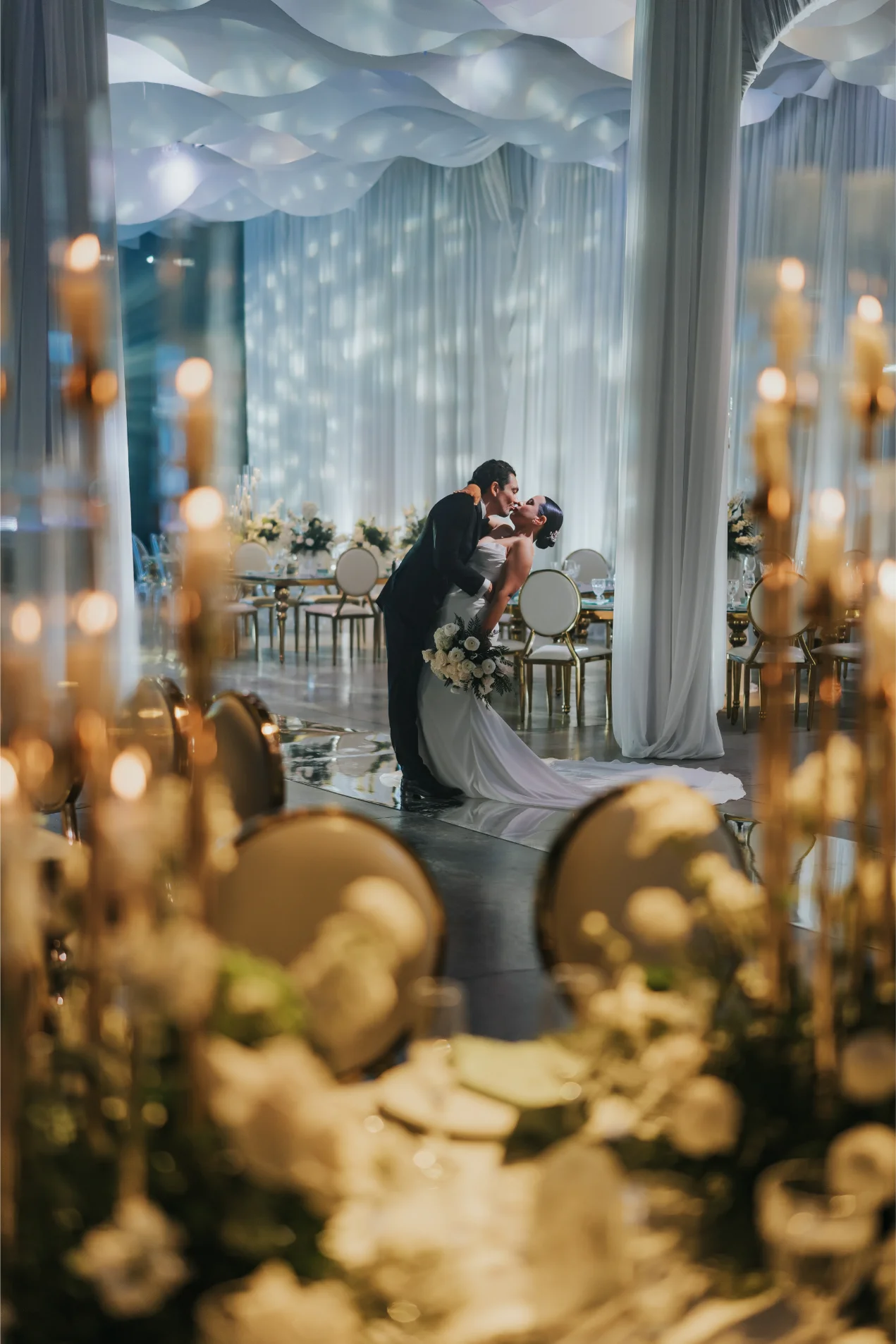 Boda Exequiel y Mireya, beso de los novios en el salón entre velas y sillas doradas
