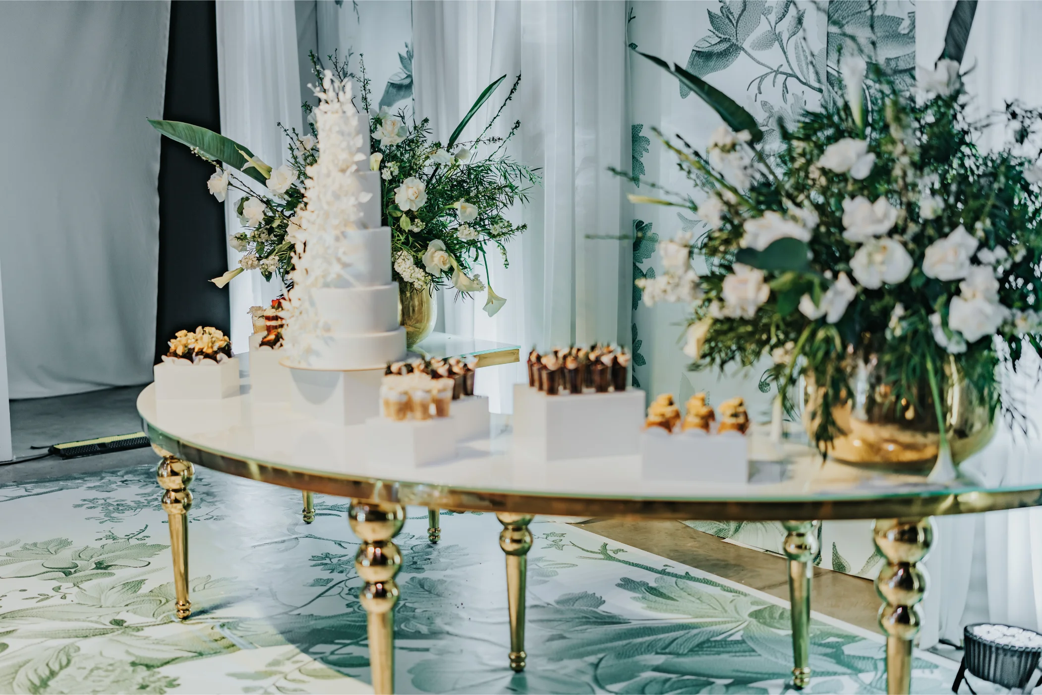 Boda Exequiel y Mireya, mesa de torta blanca de varios pisos con arreglos florales sobre base dorada