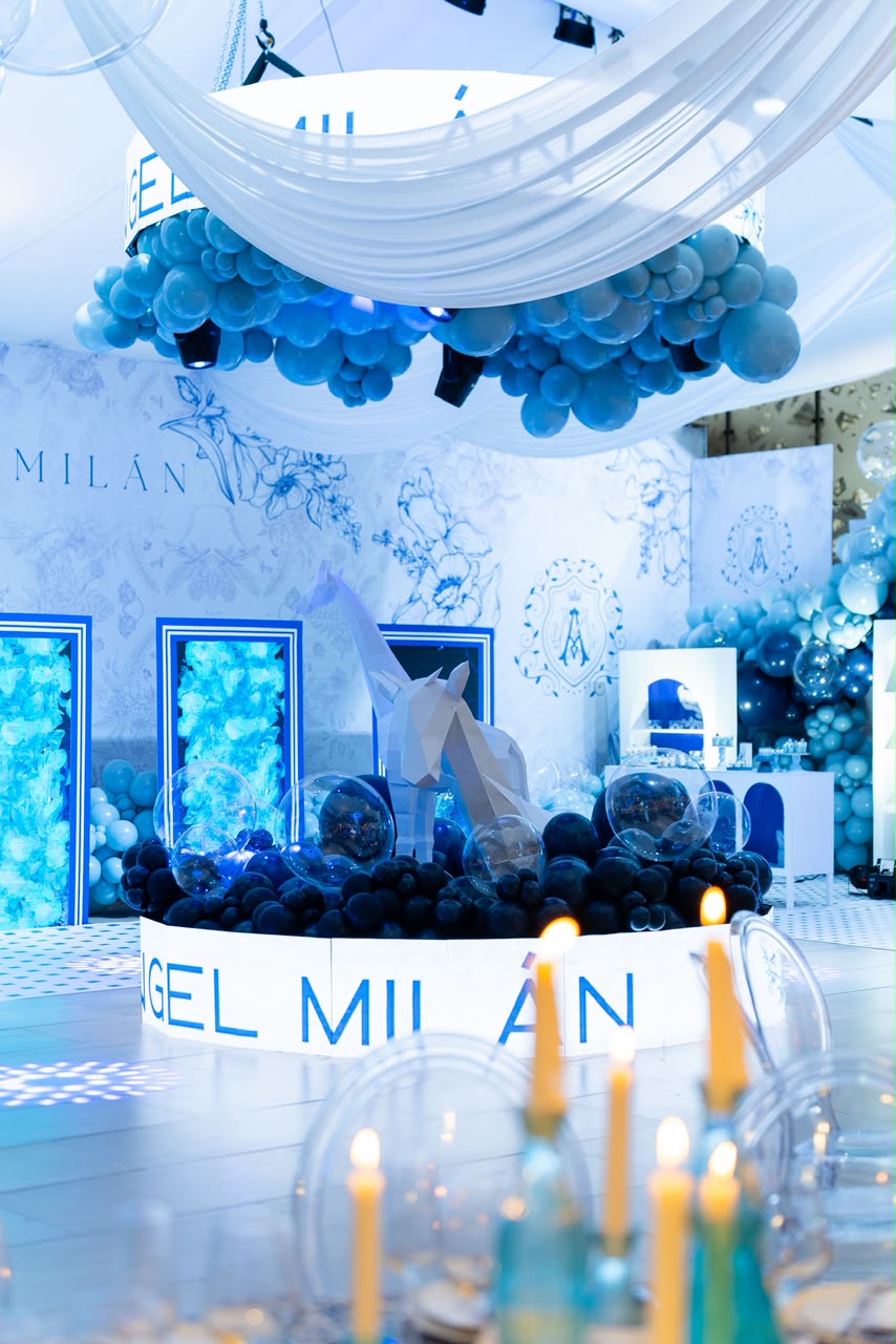 Salón con globos azules suspendidos, escultura de jirafa y montaje temático Ángel Milán