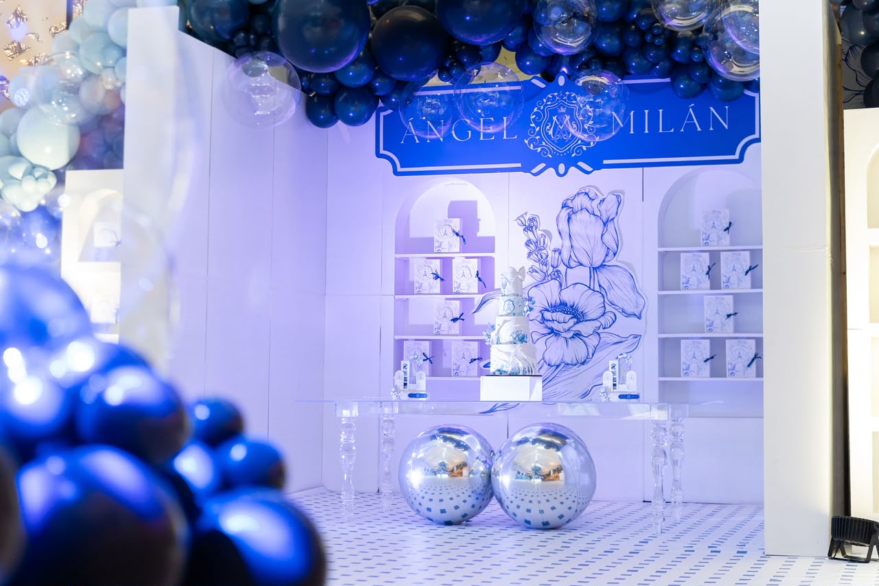 Mesa de torta con globos azules, esferas espejadas y mural floral en azul