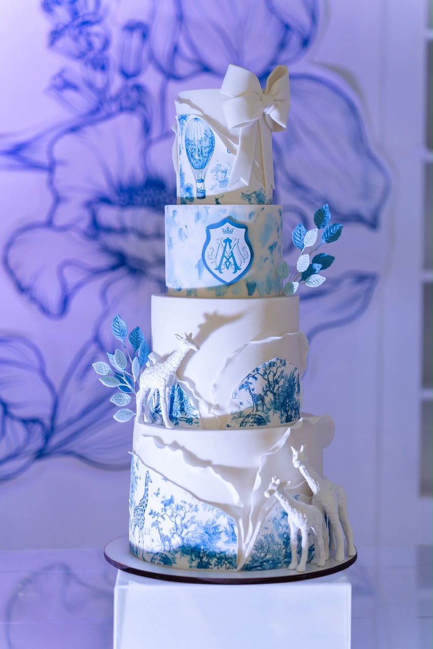 Torta de cuatro pisos pintada a mano en azul con jirafas y detalles toile